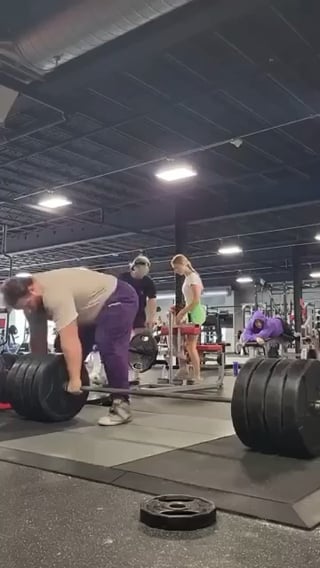 Man lifts 405 pound weight from the side, flips it onto his back, and does squats with it