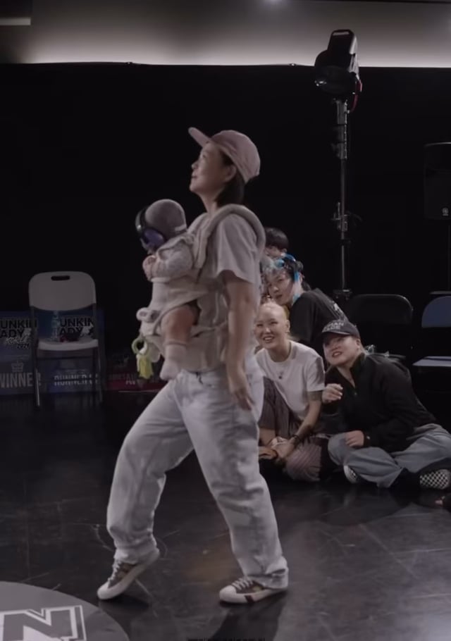 A mom doing the ‘waves’ while carrying her baby in carrier